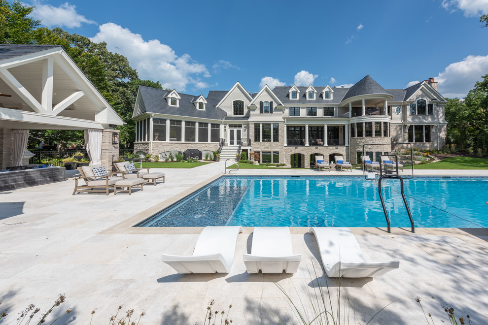 Ejemplo de casa de la piscina y piscina tradicional extra grande rectangular en patio trasero con adoquines de piedra natural