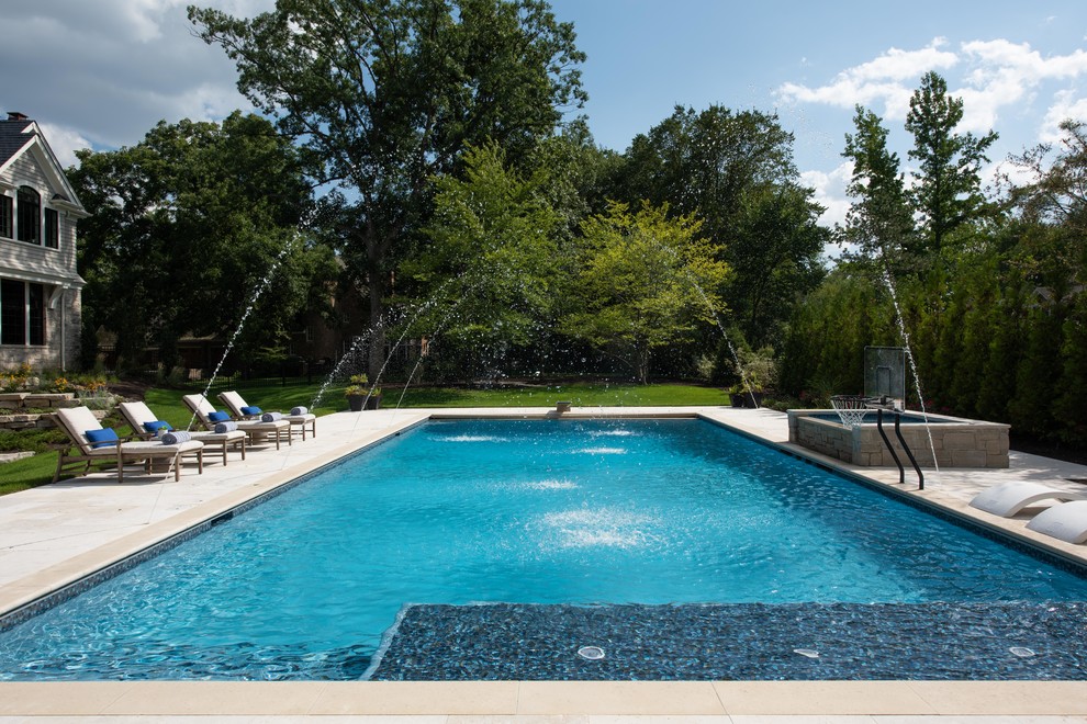 Réalisation d'un très grand Abris de piscine et pool houses arrière tradition rectangle avec des pavés en pierre naturelle.