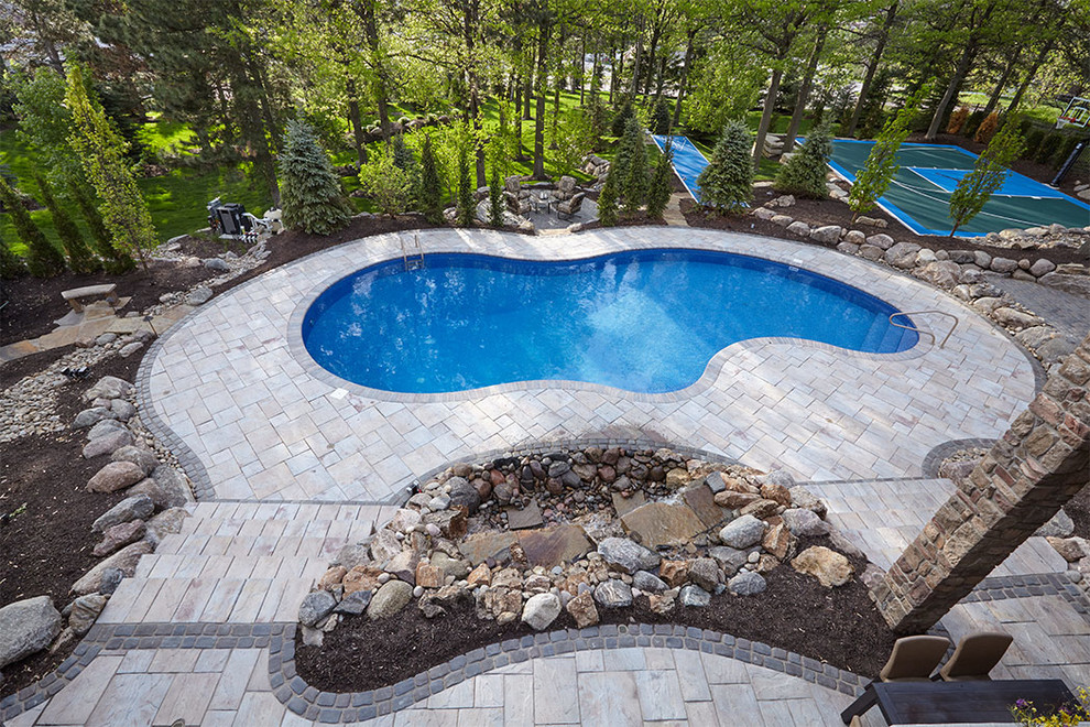 Ejemplo de casa de la piscina y piscina a medida en patio trasero con adoquines de piedra natural