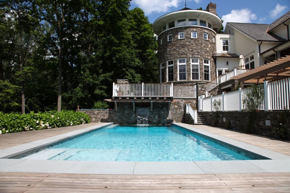 Elegant backyard rectangular lap pool fountain photo in New York with decking