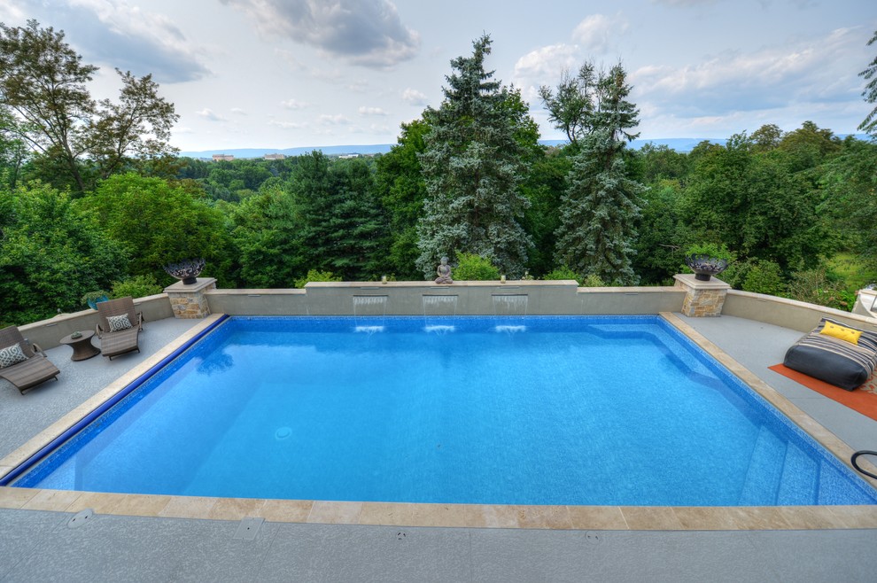 Diseño de piscina con fuente alargada minimalista de tamaño medio rectangular en patio trasero con losas de hormigón