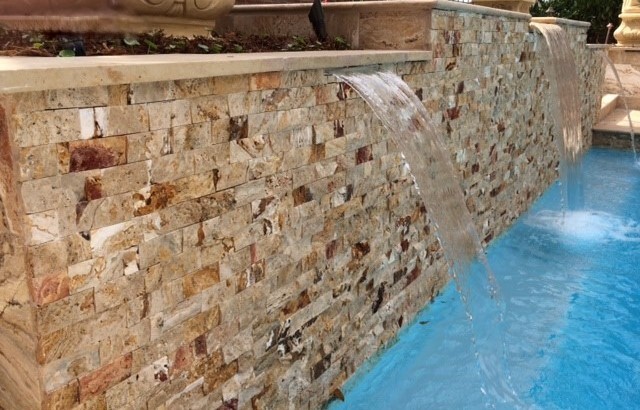 Medium sized retro courtyard custom shaped lengths swimming pool in Other with a water feature and natural stone paving.