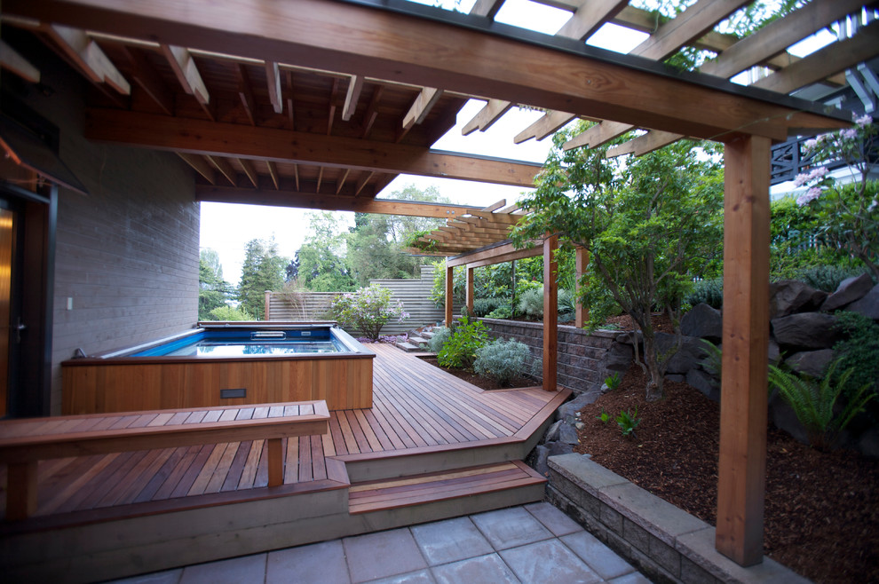Diseño de piscina alargada actual grande rectangular en patio lateral con entablado