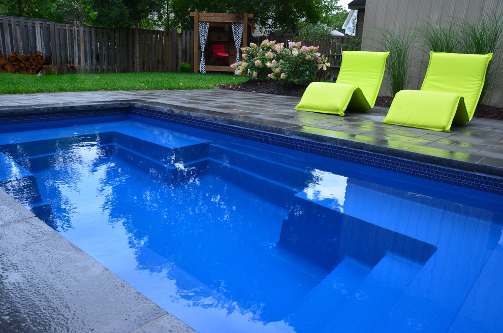 Modelo de piscina contemporánea pequeña rectangular en patio trasero con adoquines de hormigón