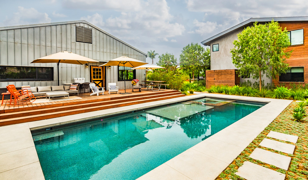 Immagine di una piscina monocorsia minimalista rettangolare di medie dimensioni e dietro casa con una vasca idromassaggio e lastre di cemento