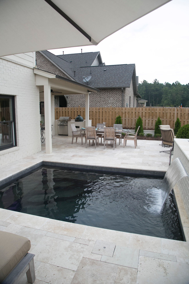 Bild på en liten rektangulär pool på baksidan av huset, med naturstensplattor