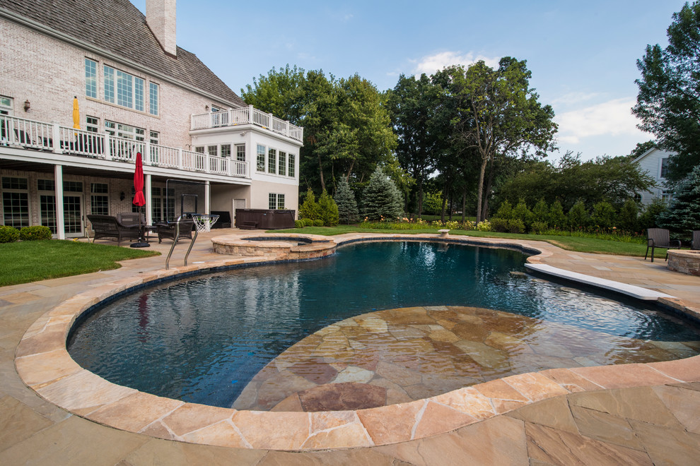 На фото: большой естественный бассейн произвольной формы на заднем дворе в стиле рустика с водной горкой и покрытием из каменной брусчатки