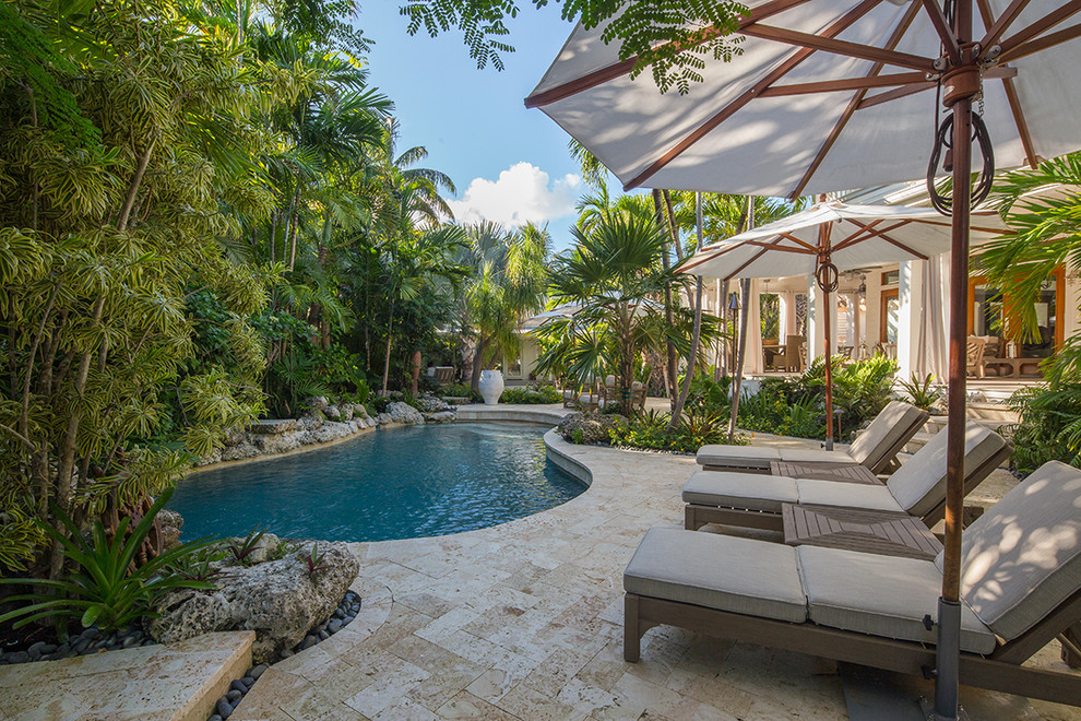 Großer Pool neben dem Haus in Nierenform mit Natursteinplatten in Miami