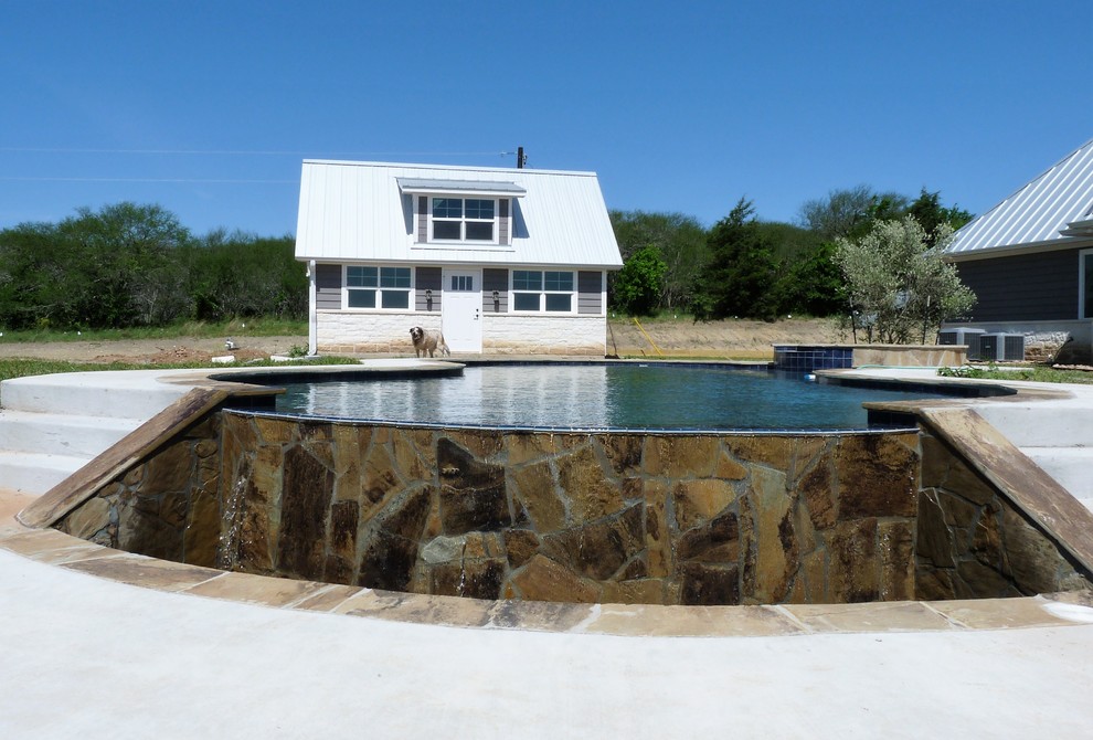 Foto di una grande piscina a sfioro infinito minimalista personalizzata in cortile con una vasca idromassaggio e pavimentazioni in cemento