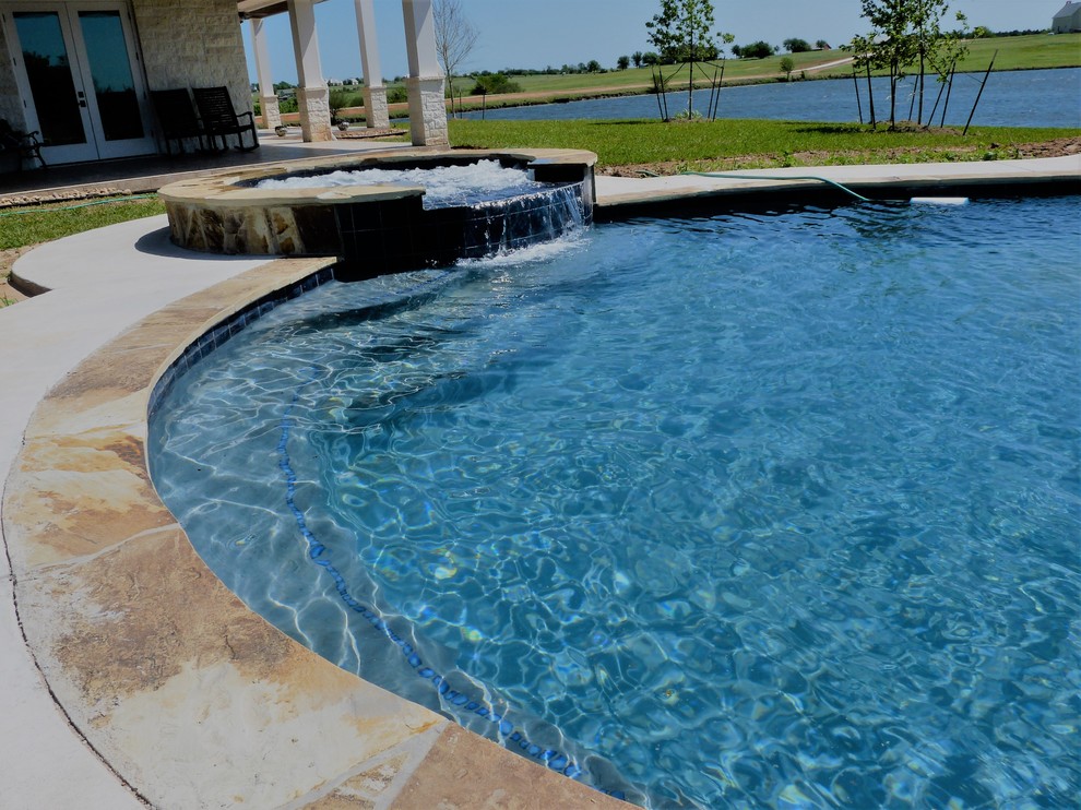 Inspiration pour une grande piscine à débordement minimaliste sur mesure avec un bain bouillonnant, une cour et des pavés en béton.