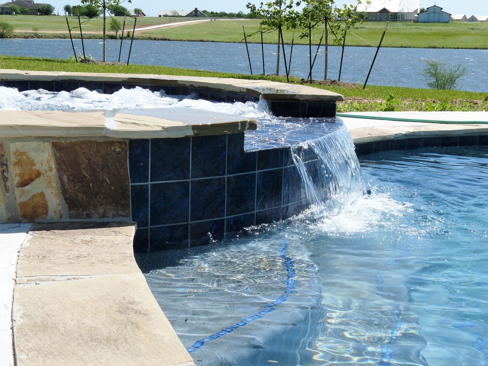 Réalisation d'une grande piscine à débordement minimaliste sur mesure avec un bain bouillonnant, une cour et des pavés en béton.