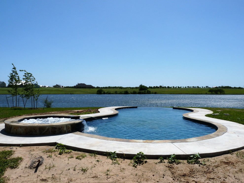 Cette image montre une grande piscine à débordement minimaliste sur mesure avec une cour, un bain bouillonnant et des pavés en béton.
