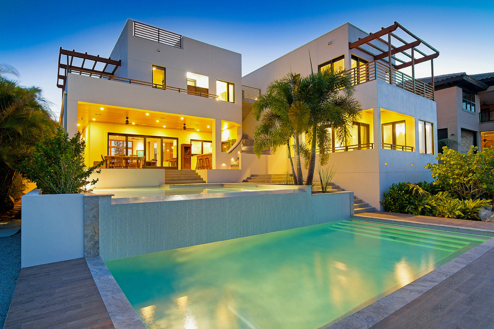 Foto di una grande piscina a sfioro infinito moderna personalizzata dietro casa con una vasca idromassaggio e piastrelle