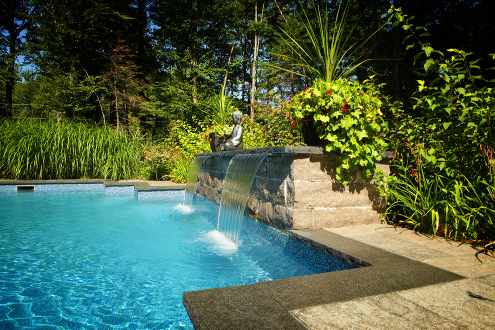 Cette image montre une piscine naturelle et arrière minimaliste rectangle avec un point d'eau et des pavés en pierre naturelle.