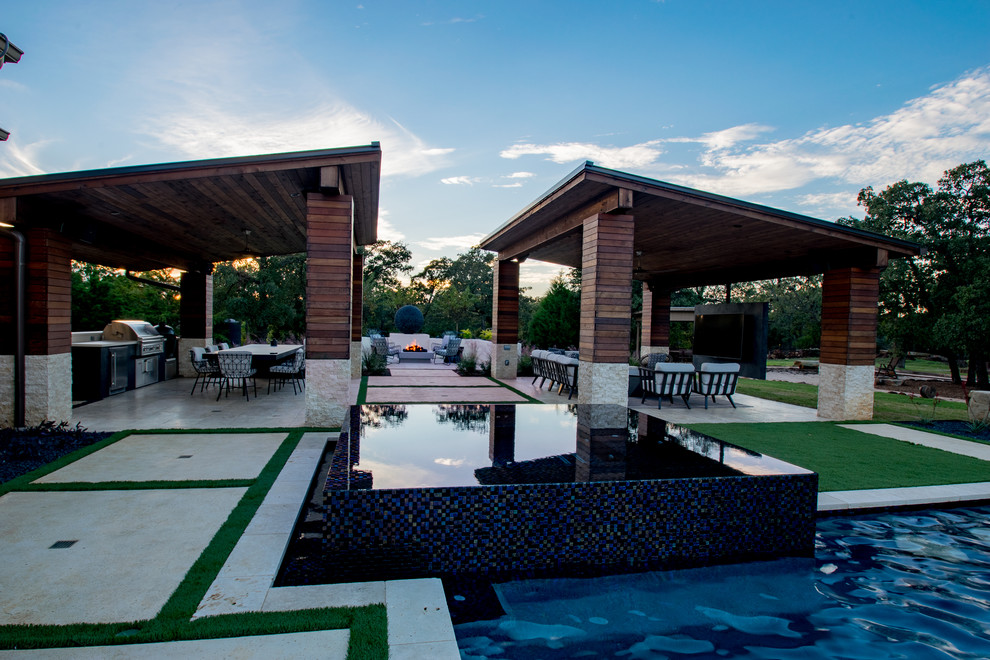Ejemplo de piscina con fuente infinita tradicional renovada extra grande a medida en patio trasero con adoquines de piedra natural