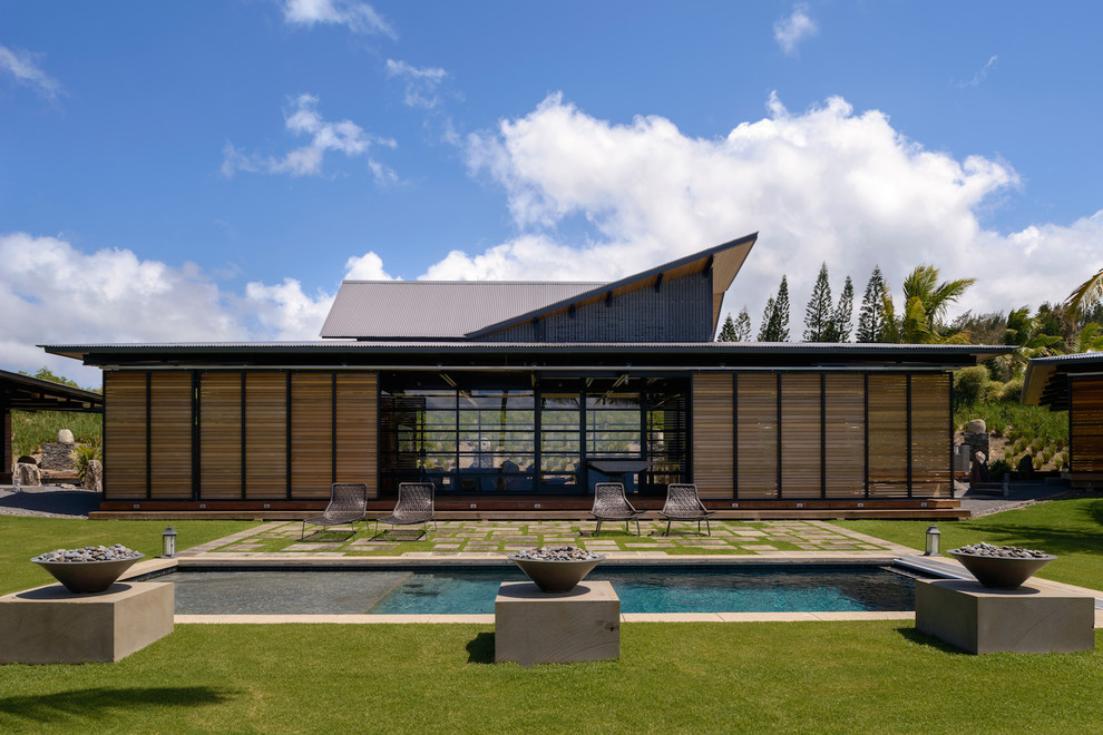 Ispirazione per una piscina monocorsia design rettangolare dietro casa con pavimentazioni in pietra naturale