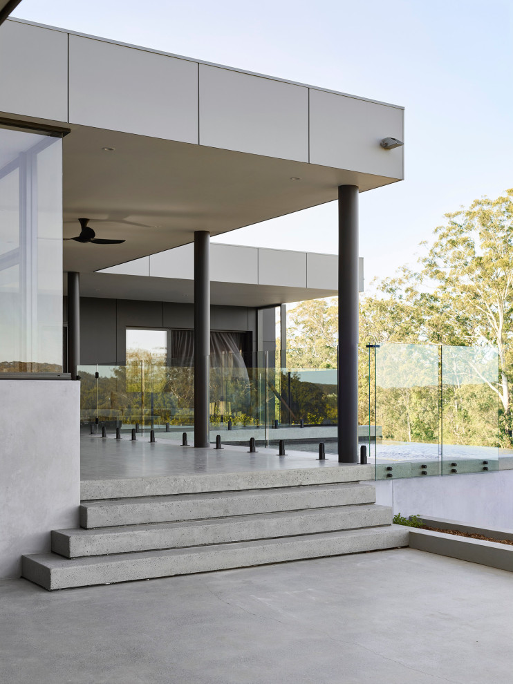 Immagine di una grande piscina a sfioro infinito moderna personalizzata in cortile con lastre di cemento