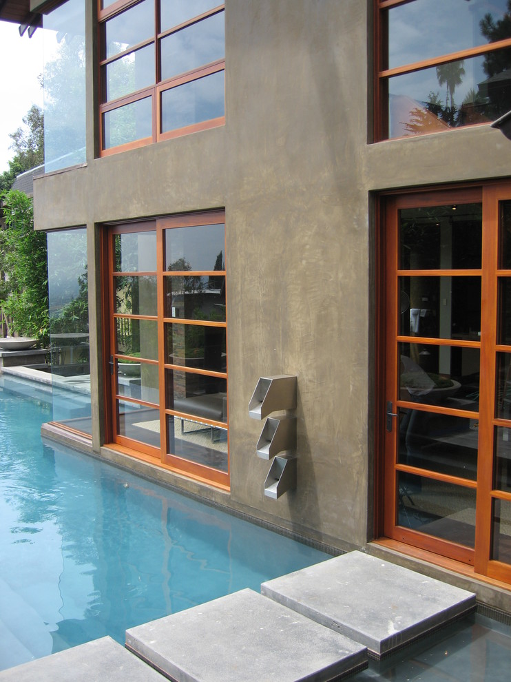 Diseño de piscina infinita minimalista extra grande a medida en patio trasero con adoquines de hormigón