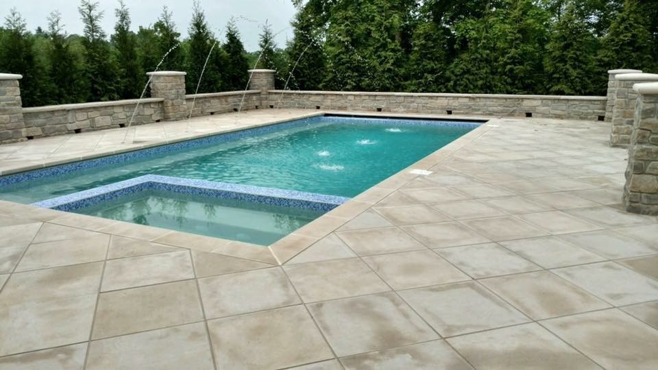 Esempio di una piscina monocorsia moderna rettangolare dietro casa e di medie dimensioni con una vasca idromassaggio e lastre di cemento
