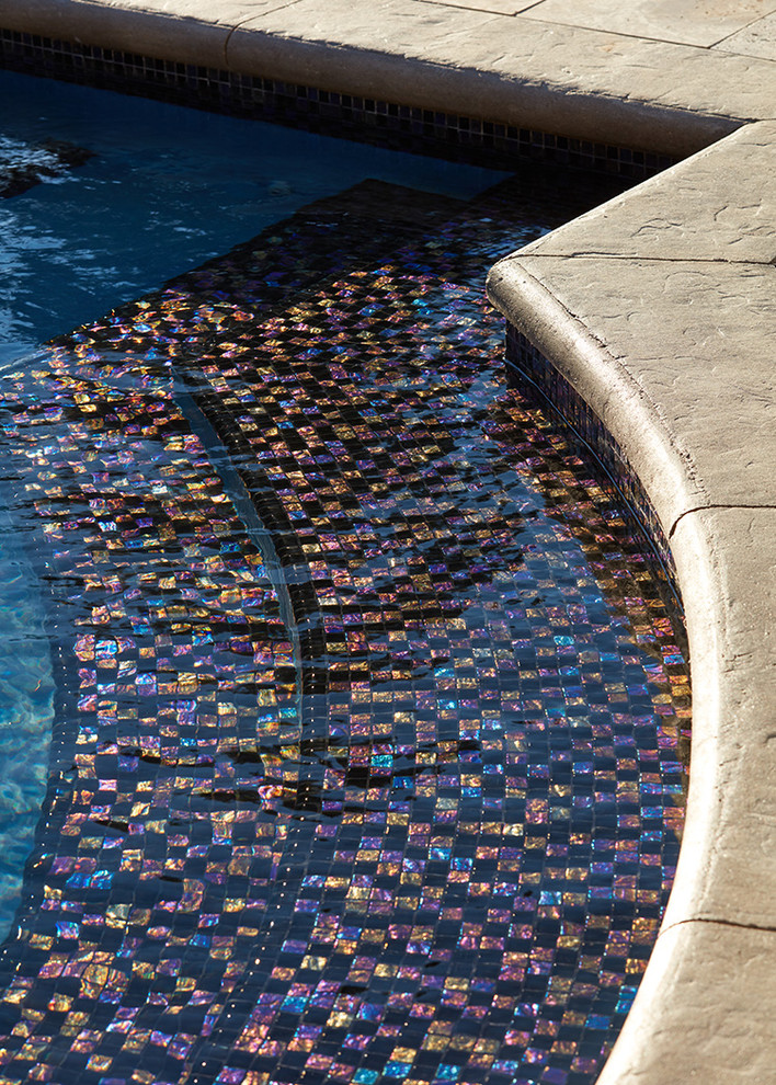 На фото: бассейн-инфинити произвольной формы на заднем дворе с джакузи и покрытием из каменной брусчатки