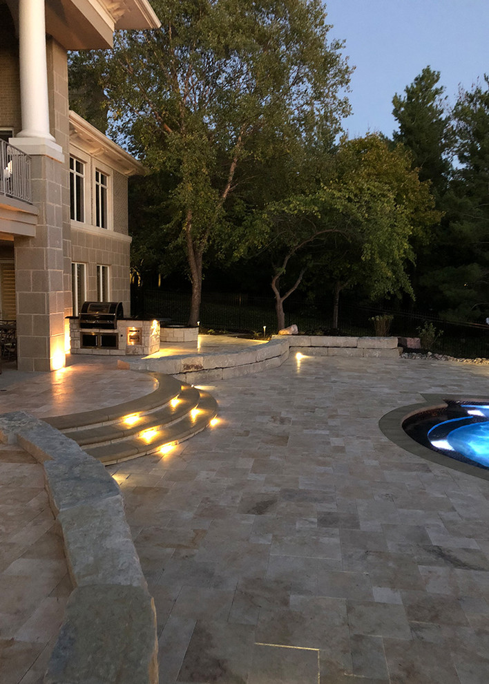 Ejemplo de piscinas y jacuzzis infinitos a medida en patio trasero con adoquines de piedra natural