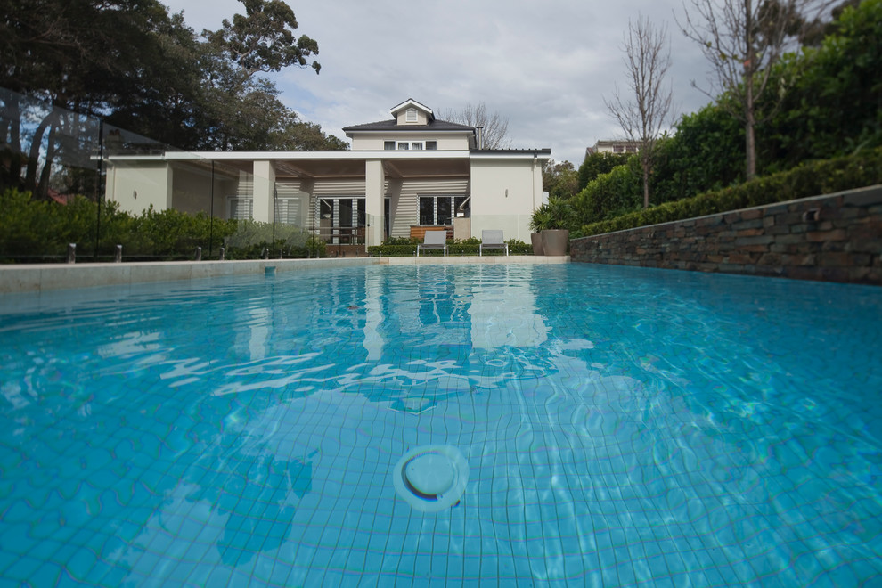 Inspiration pour une grande piscine arrière design rectangle avec un point d'eau et des pavés en pierre naturelle.