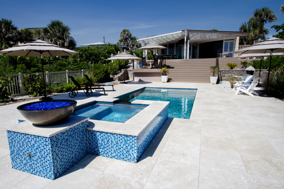 Réalisation d'une piscine design rectangle avec un bain bouillonnant et des pavés en pierre naturelle.