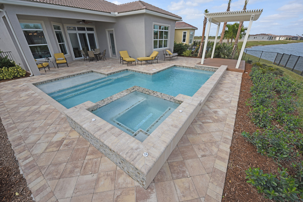 This is an example of a medium sized classic back rectangular infinity swimming pool in Miami with natural stone paving.