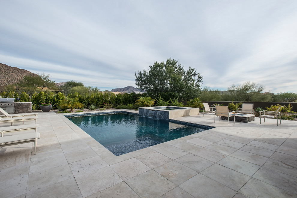 Diseño de piscina contemporánea grande rectangular en patio trasero con adoquines de piedra natural