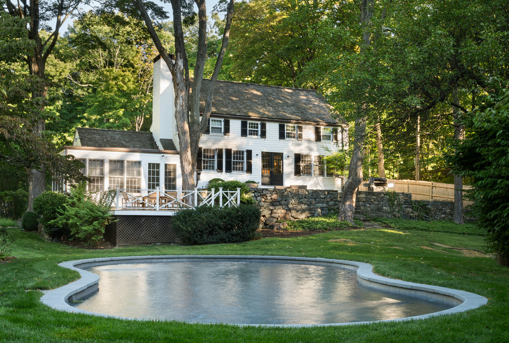 Modelo de piscina de estilo de casa de campo tipo riñón en patio trasero con adoquines de piedra natural