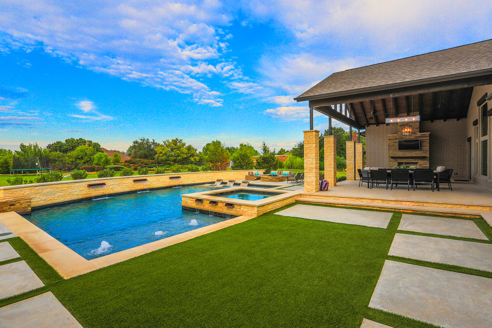 Diseño de piscina con fuente alargada tradicional renovada grande en forma de L en patio trasero con losas de hormigón