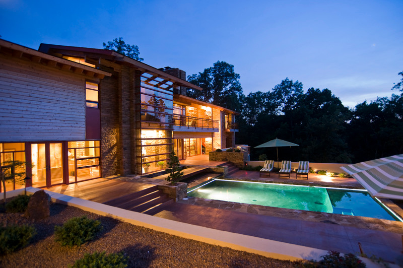 Esempio di una grande piscina monocorsia contemporanea rettangolare dietro casa con una dépendance a bordo piscina e pavimentazioni in pietra naturale