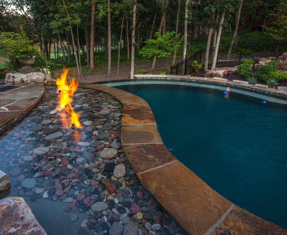 Imagen de piscina tropical grande a medida en patio trasero con adoquines de piedra natural