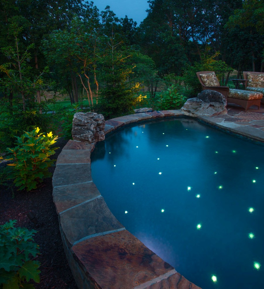 Diseño de piscina tropical grande a medida en patio trasero con adoquines de piedra natural