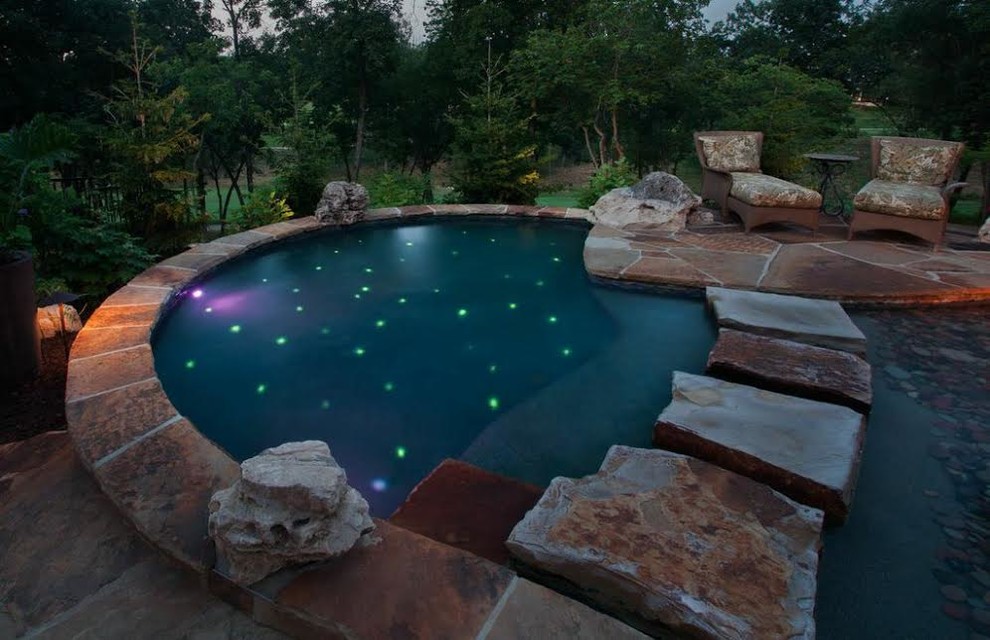 Large world-inspired back custom shaped swimming pool in Kansas City with natural stone paving.