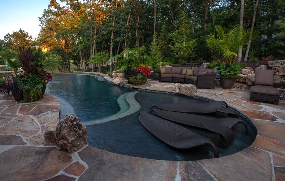 Exemple d'une grande piscine arrière exotique sur mesure avec des pavés en pierre naturelle.