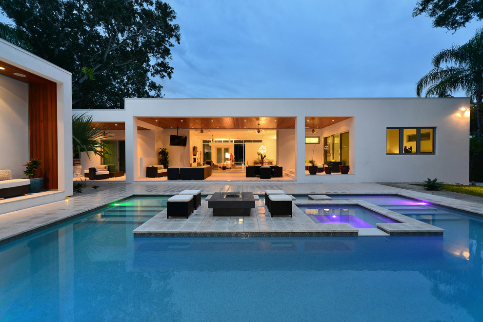 Пример оригинального дизайна: бассейн произвольной формы на заднем дворе в стиле модернизм с мощением тротуарной плиткой и джакузи