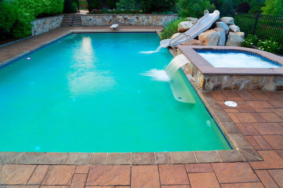 Ejemplo de piscinas y jacuzzis naturales tradicionales grandes rectangulares en patio trasero con adoquines de hormigón