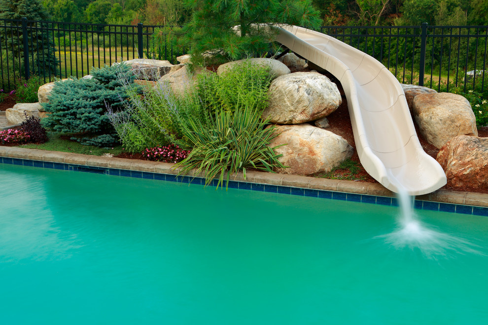 Immagine di una grande piscina tradizionale rettangolare dietro casa con un acquascivolo e pavimentazioni in cemento