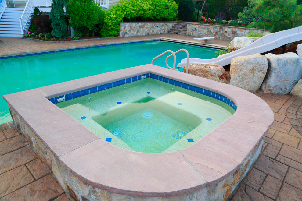 Ispirazione per una grande piscina naturale chic rettangolare dietro casa con una vasca idromassaggio e pavimentazioni in cemento