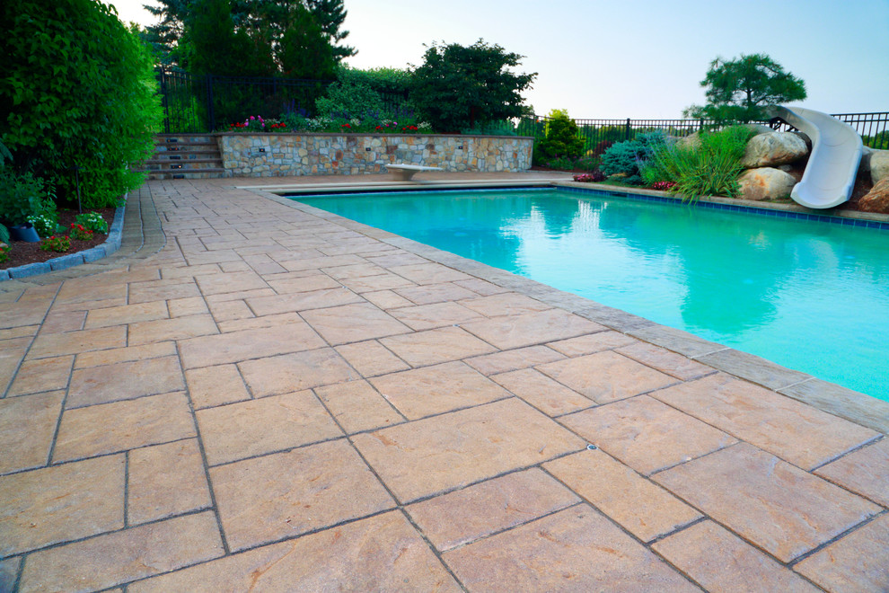 Idee per una grande piscina naturale tradizionale rettangolare dietro casa con un acquascivolo e pavimentazioni in cemento
