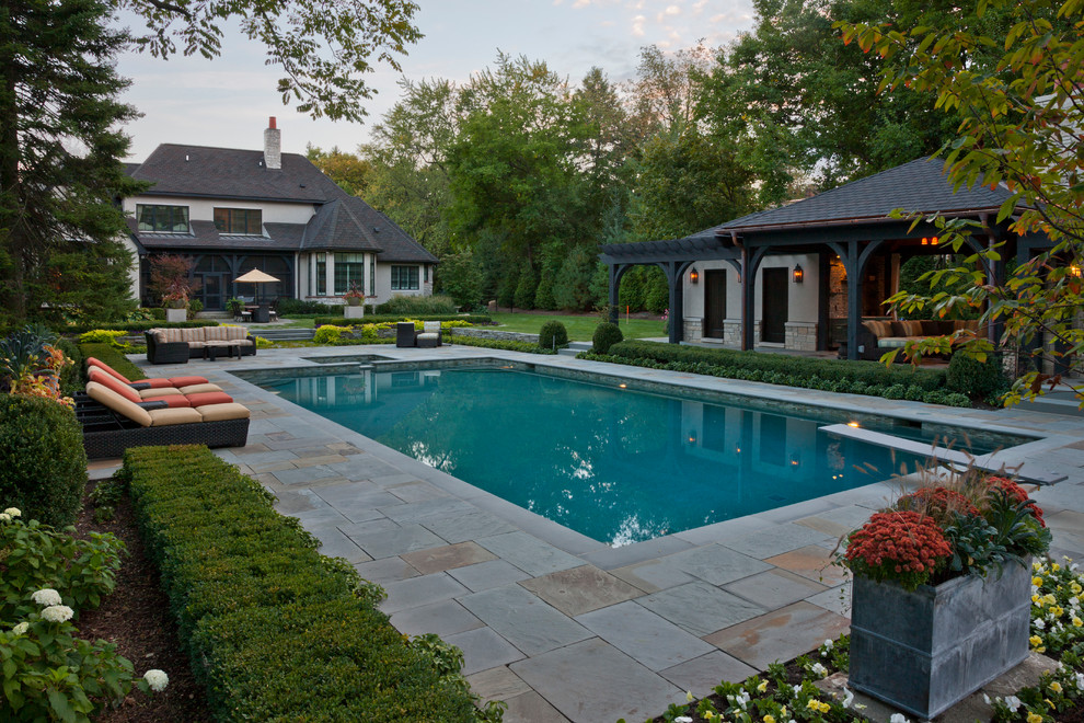Ejemplo de casa de la piscina y piscina tradicional renovada de tamaño medio rectangular en patio trasero con adoquines de piedra natural