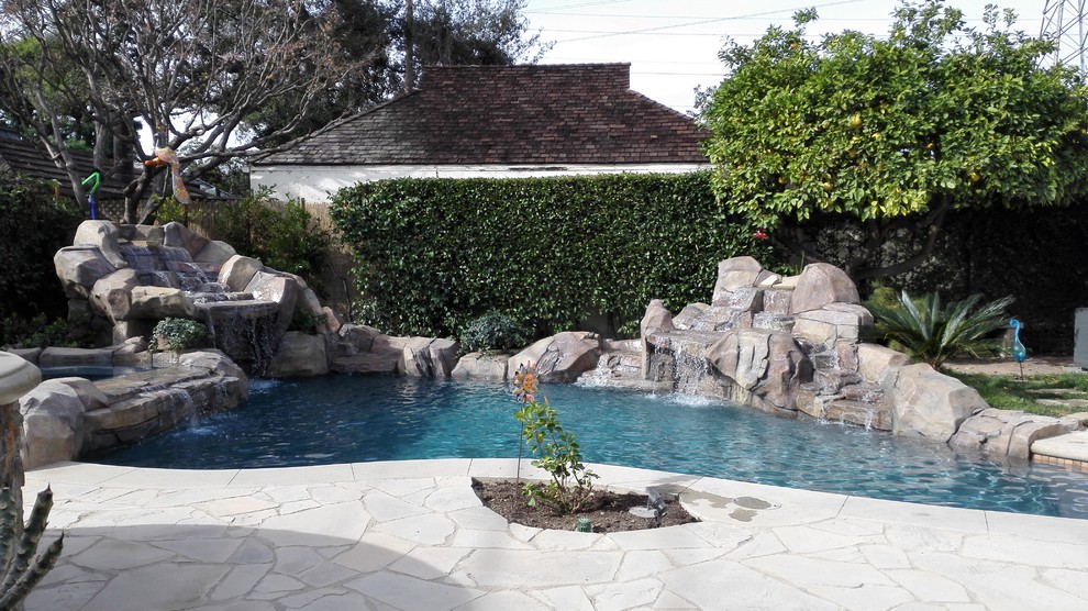 Foto di una piccola piscina tropicale personalizzata dietro casa con fontane e pavimentazioni in pietra naturale