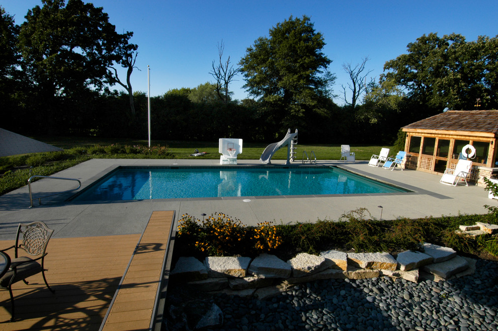Modelo de piscina alargada mediterránea de tamaño medio rectangular en patio trasero con losas de hormigón