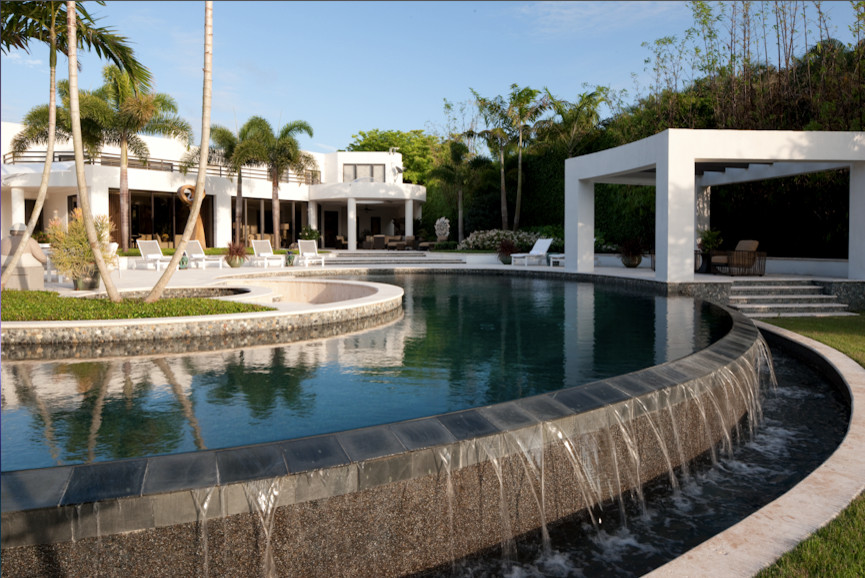 Esempio di un'ampia piscina a sfioro infinito contemporanea personalizzata dietro casa con pavimentazioni in pietra naturale