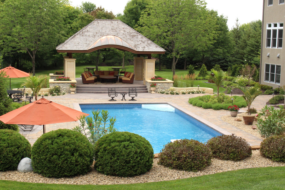 Foto de casa de la piscina y piscina clásica de tamaño medio rectangular en patio trasero con adoquines de hormigón