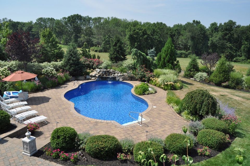 Large elegant backyard concrete paver and custom-shaped natural pool fountain photo in New York