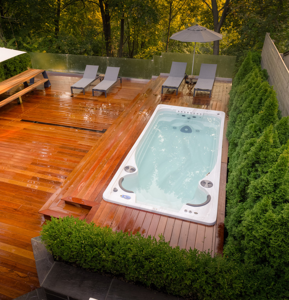 Réalisation d'un couloir de nage arrière minimaliste rectangle avec un bain bouillonnant et une terrasse en bois.