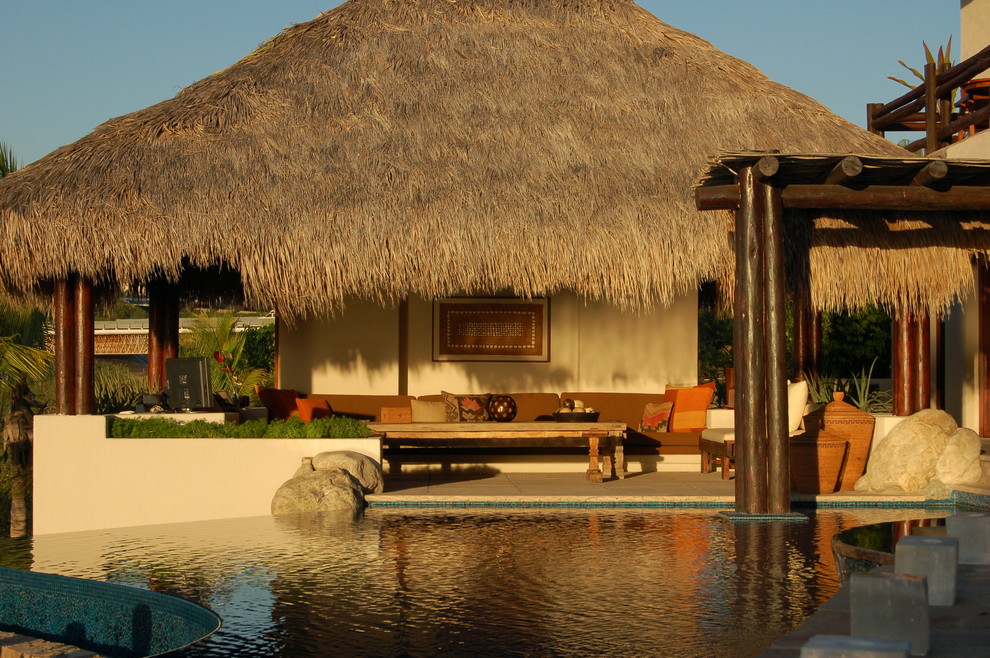 Diseño de casa de la piscina y piscina infinita tropical grande rectangular en patio lateral con adoquines de piedra natural