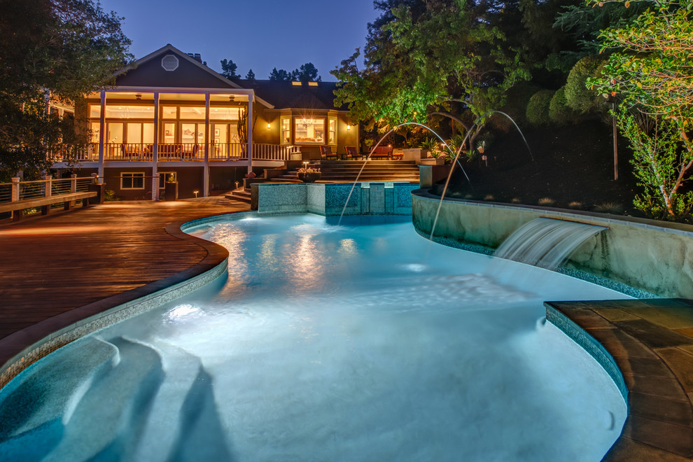Idée de décoration pour une piscine arrière design sur mesure avec un point d'eau et une terrasse en bois.